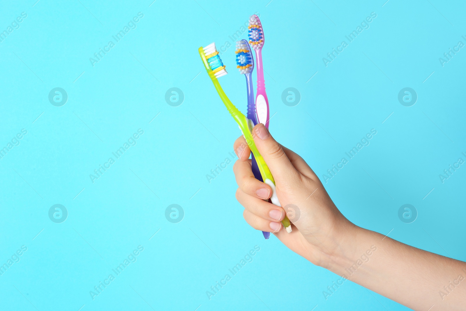 Photo of Woman holding manual toothbrushes against color background