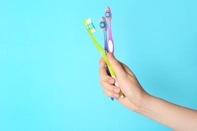 Woman holding manual toothbrushes against color background