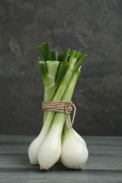 Photo of Bunch of green spring onions on grey wooden table