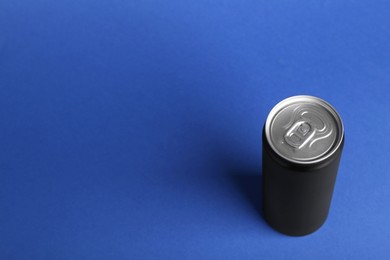 Photo of Energy drink in black can on blue background, above view. Space for text