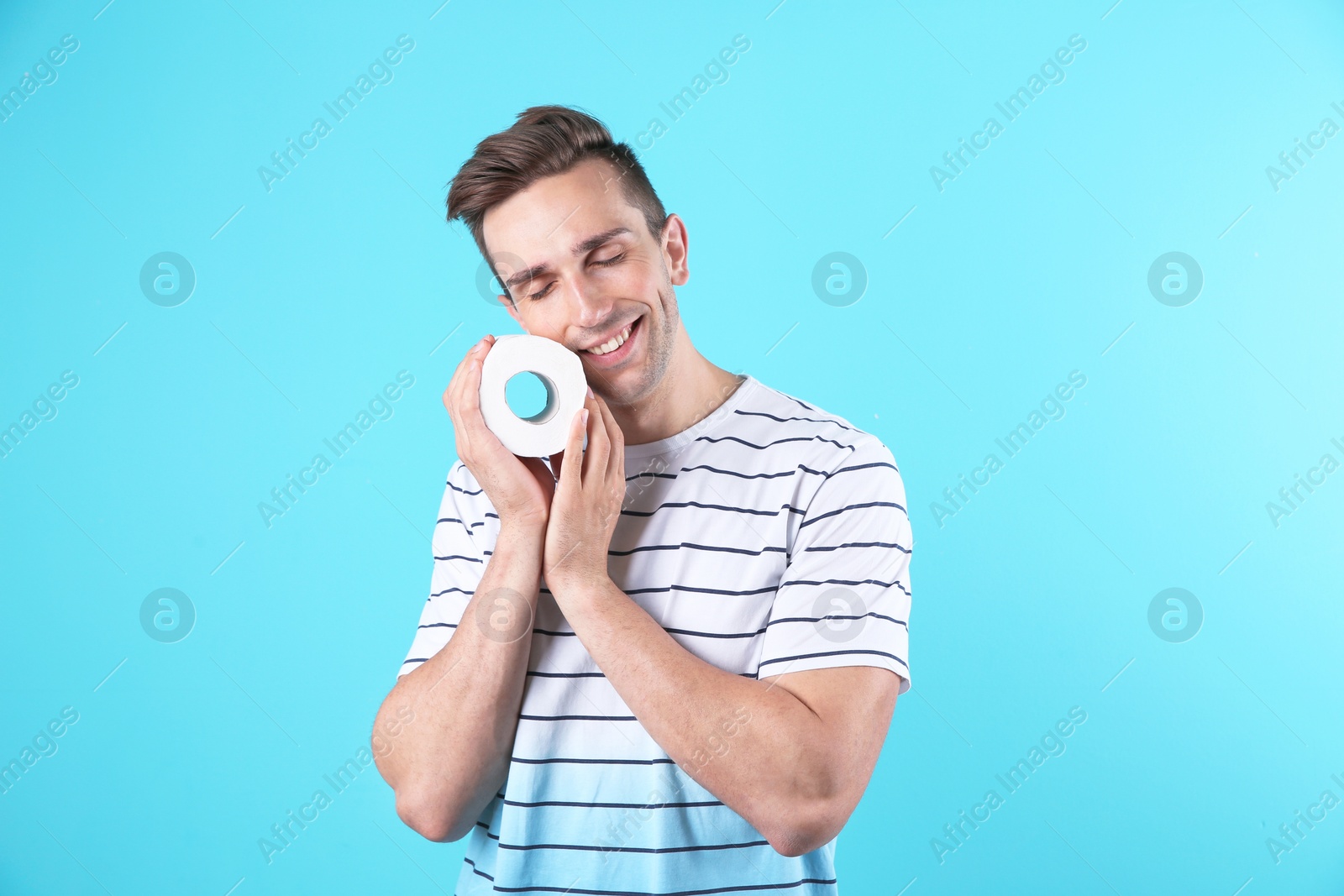 Photo of Young man holding toilet paper roll on color background