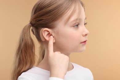 Photo of Little girl with hearing aid on pale brown background