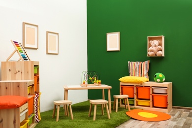 Stylish playroom interior with table and stools