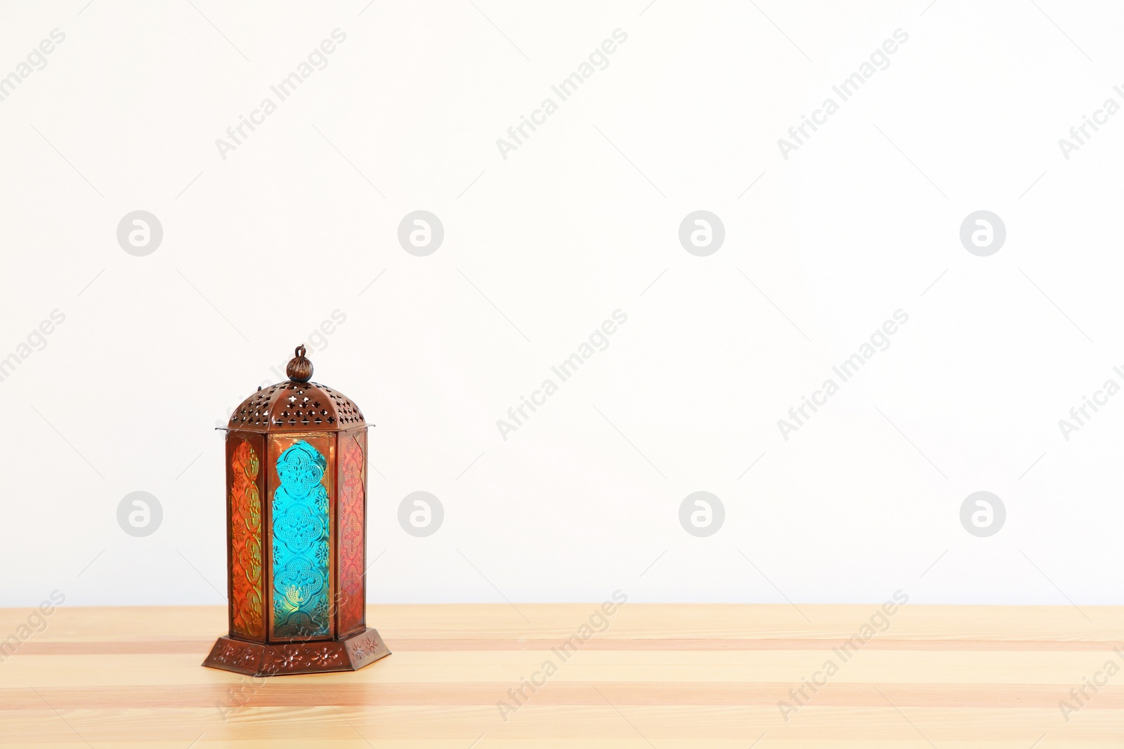 Photo of Muslim lantern Fanous on table against light background. Space for text