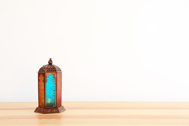 Photo of Muslim lantern Fanous on table against light background. Space for text