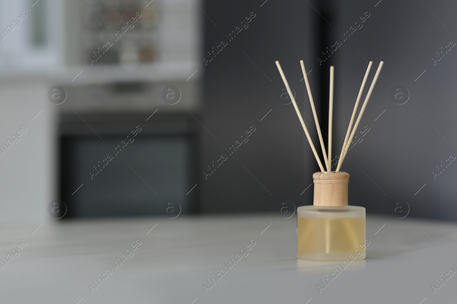 Photo of Aromatic reed air freshener on table indoors. Space for text