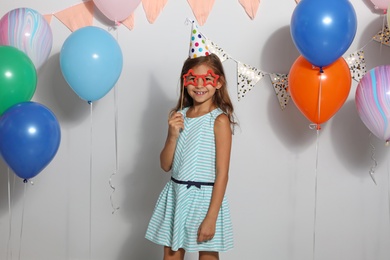 Happy girl near bright balloons at birthday party indoors