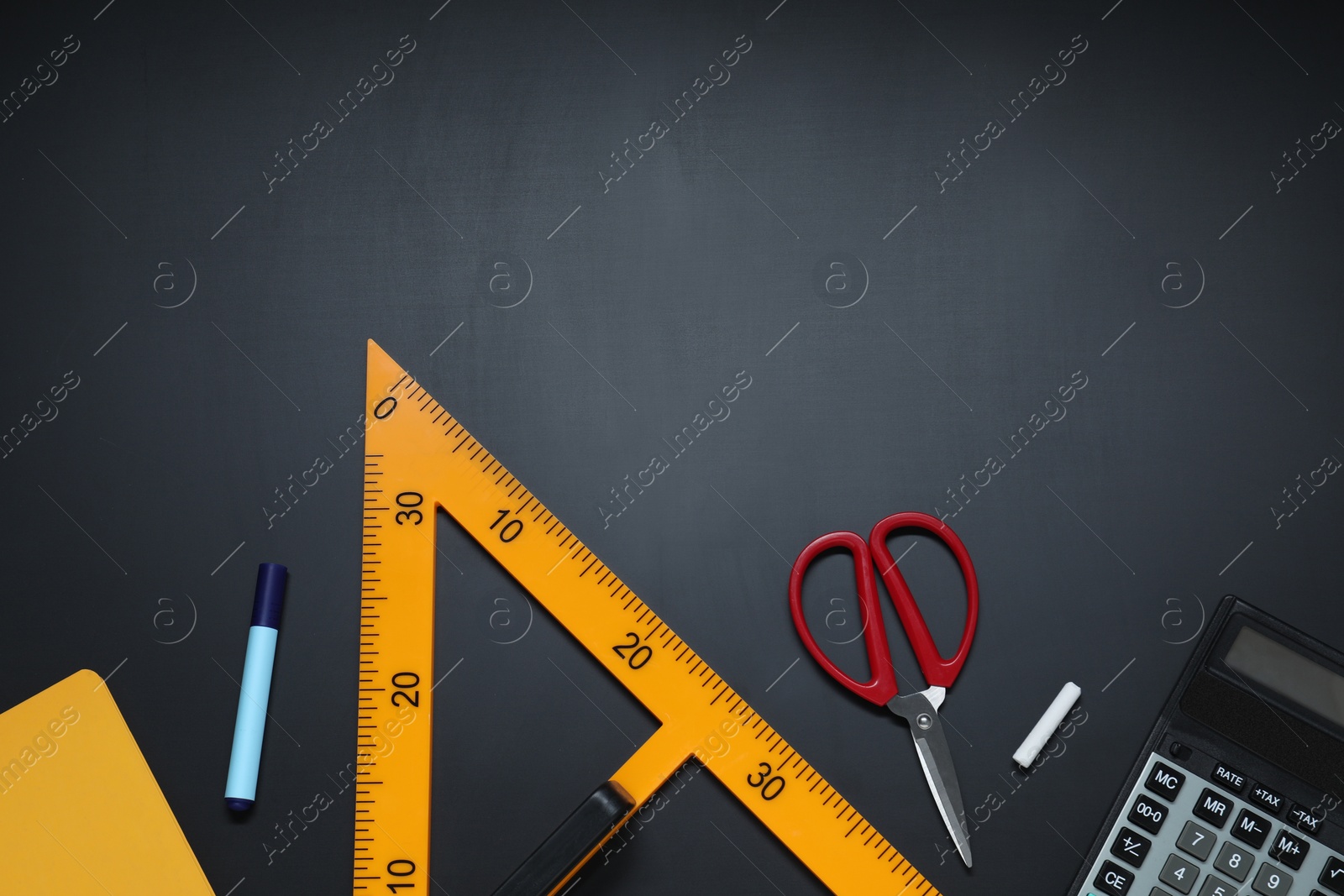 Photo of Triangle ruler, scissors, chalk, calculator, marker and notebook on black table, flat lay. Space for text