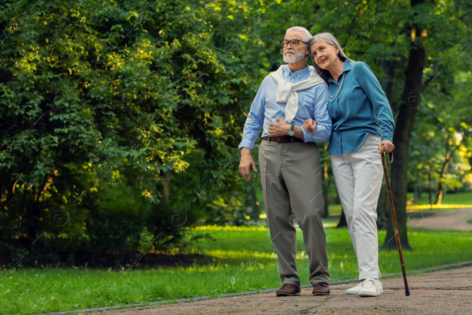 Photo of Senior man with walking cane and mature woman in park. Space for text