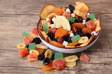 Photo of Bowl and different tasty dried fruits on wooden table