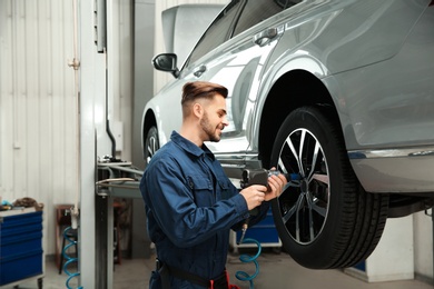 Photo of Technician working with car in automobile repair shop