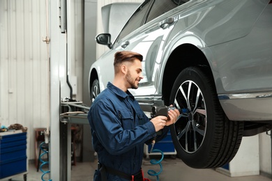 Technician working with car in automobile repair shop