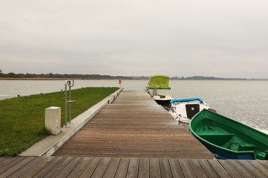 Wooden pier with moored boats near sea. Real estate