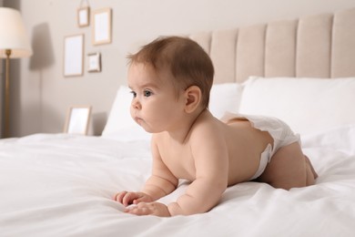 Photo of Cute little baby in diaper on bed at home
