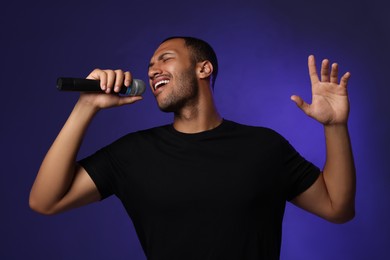 Photo of Handsome man with microphone singing on blue background