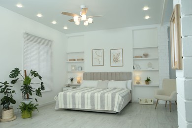 Photo of Comfortable furniture, ceiling fan, houseplants and accessories in stylish bedroom