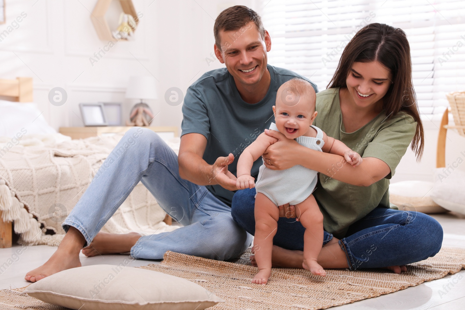 Photo of Happy family with their cute baby on floor in bedroom