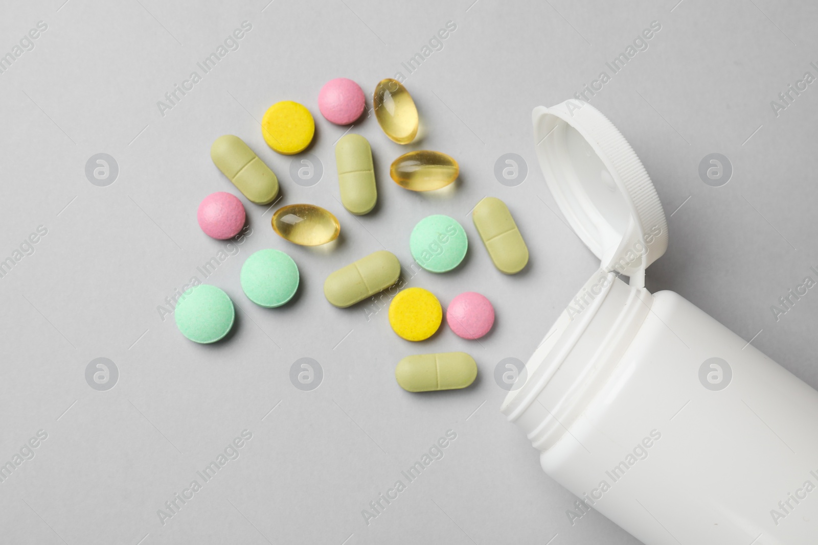 Photo of Different vitamin pills and bottle on grey background, top view