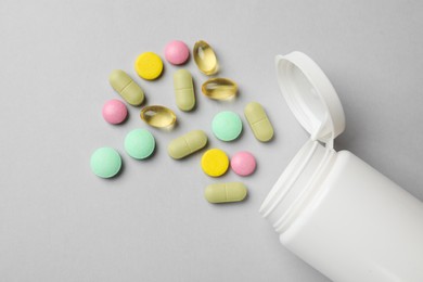 Different vitamin pills and bottle on grey background, top view