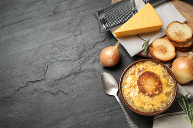 Photo of Tasty homemade french onion soup served on black table, flat lay. Space for text