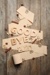 Photo of Flat lay composition with text Bye 2020 and toilet paper on wooden background, flat lay