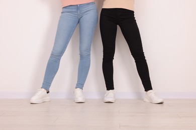 Photo of Women in stylish jeans near white wall, closeup