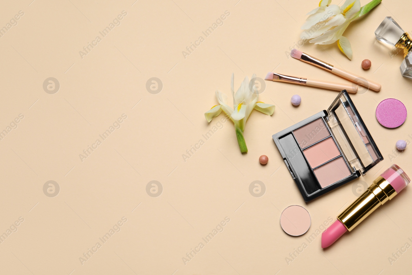 Photo of Flat lay composition with different makeup products and beautiful flowers on beige background. Space for text