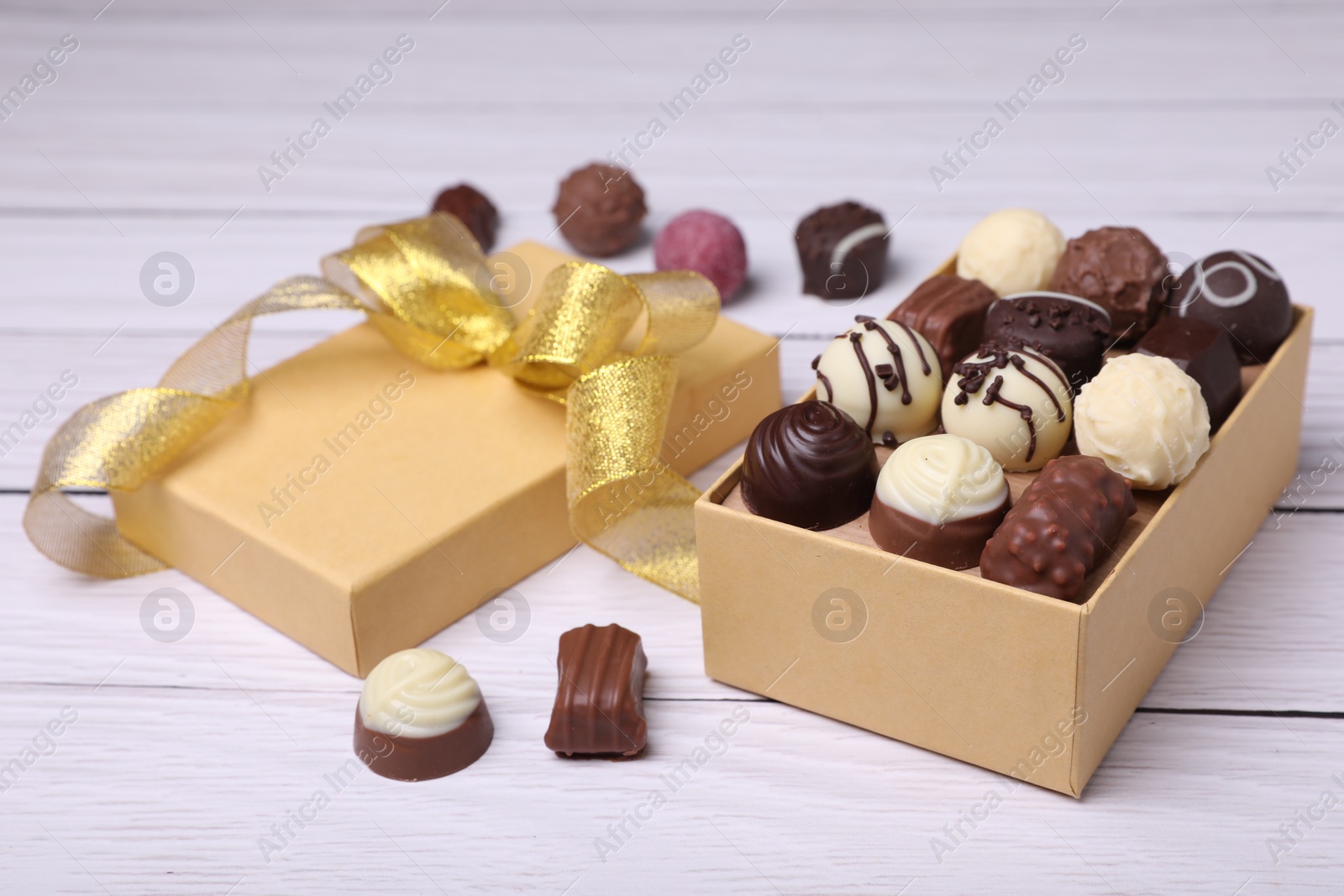 Photo of Box with tasty chocolate candies on white wooden table, closeup