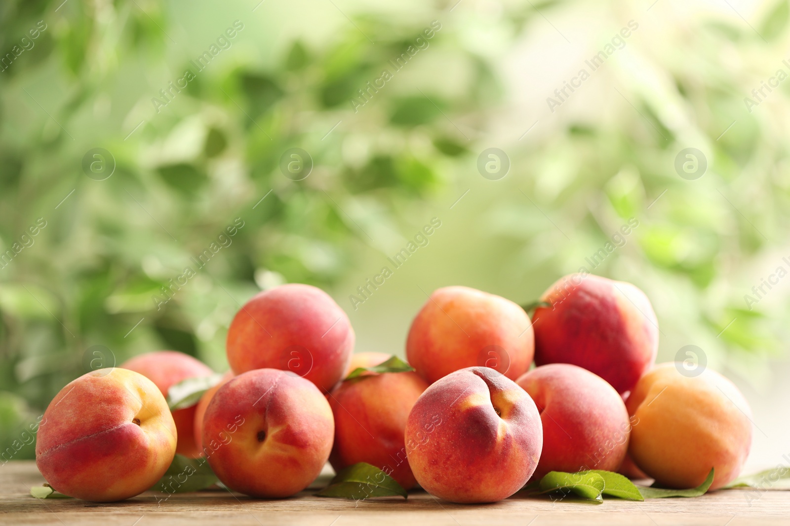 Photo of Fresh sweet peaches on wooden table outdoors