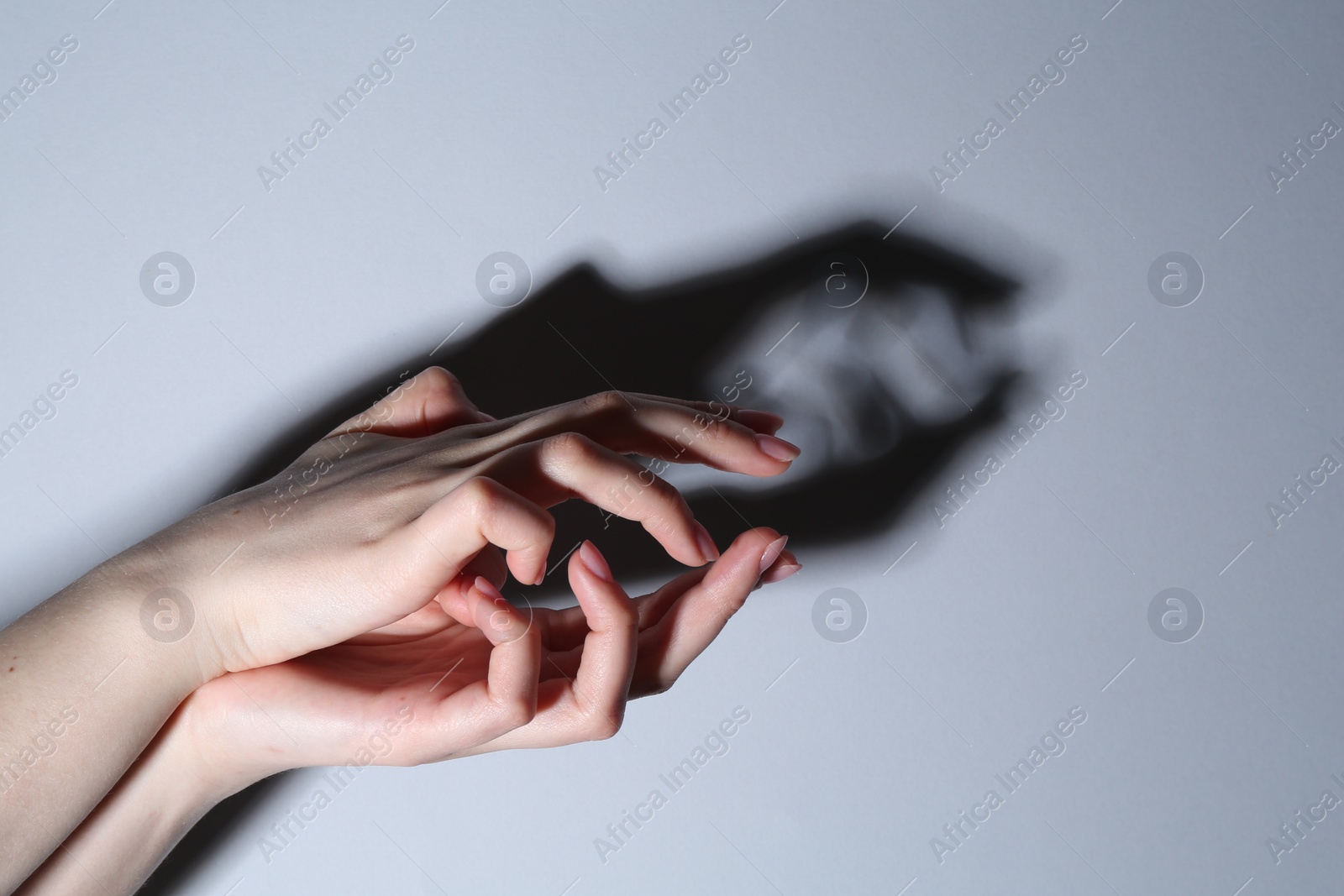 Photo of Shadow puppet. Woman making hand gesture like crocodile on grey background, closeup