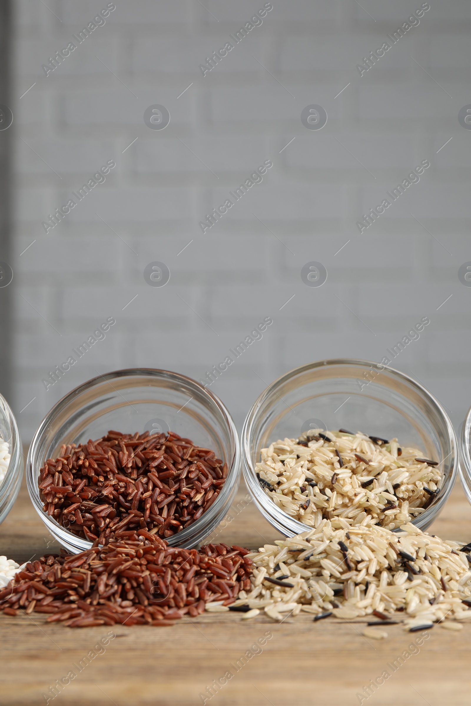 Photo of Different types of rice on wooden table, closeup