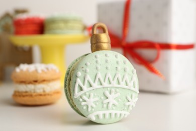 Photo of Beautifully decorated Christmas macaron on white table, closeup
