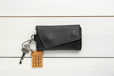 Photo of Leather case with key on white wooden table, top view