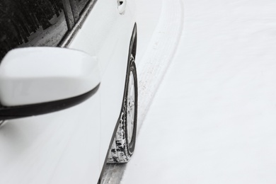 Photo of Modern car leaving tire track on snowy road, closeup view