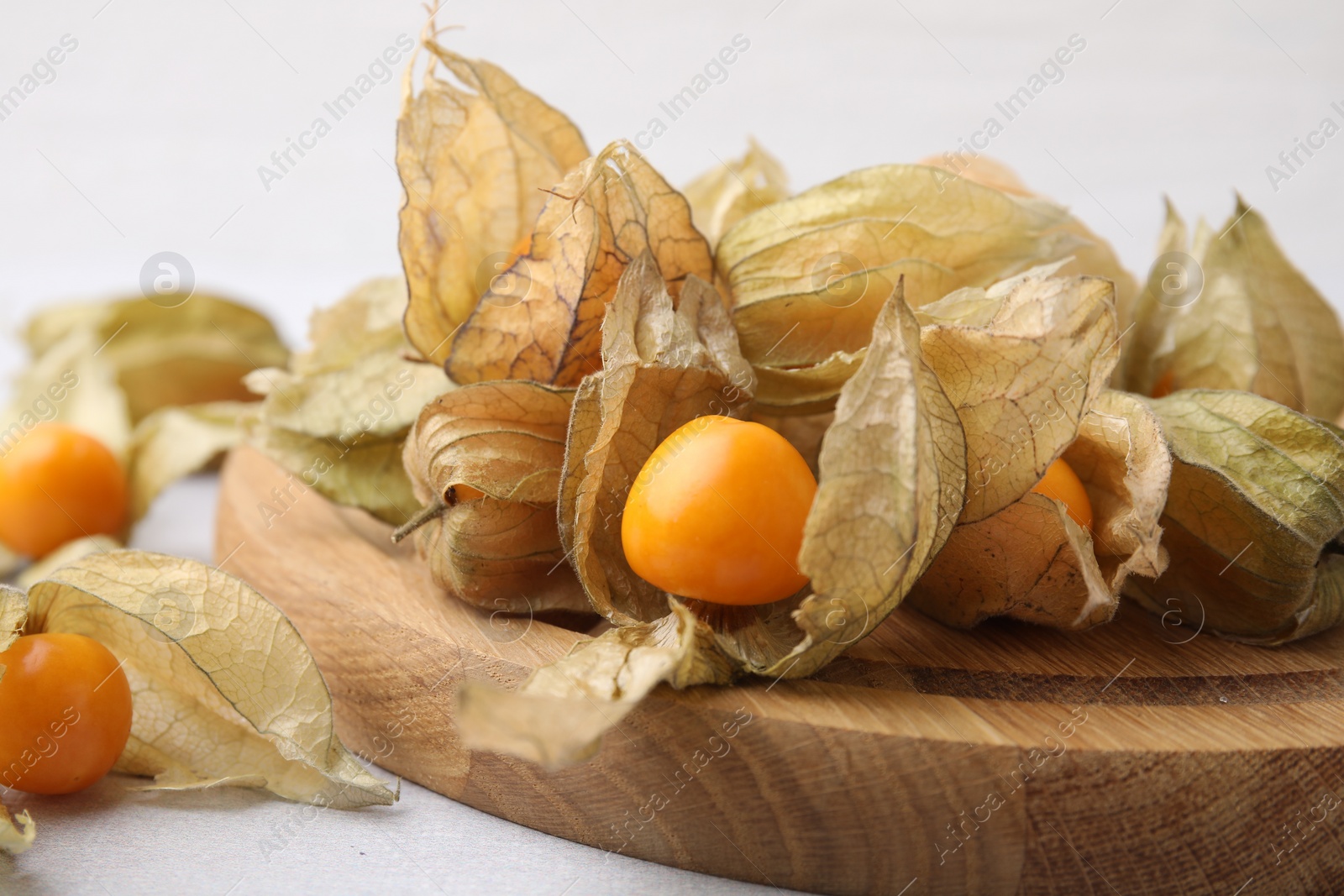 Photo of Ripe physalis fruits with calyxes on white table, closeup
