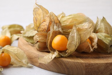 Photo of Ripe physalis fruits with calyxes on white table, closeup