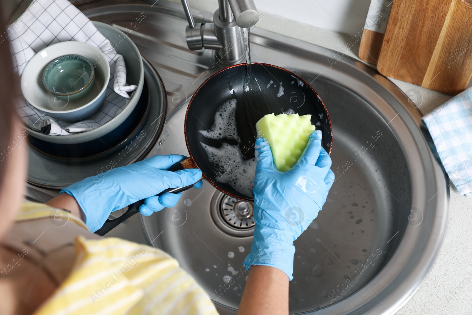 Photo of Woman washing dirty frying pan in sink, above view