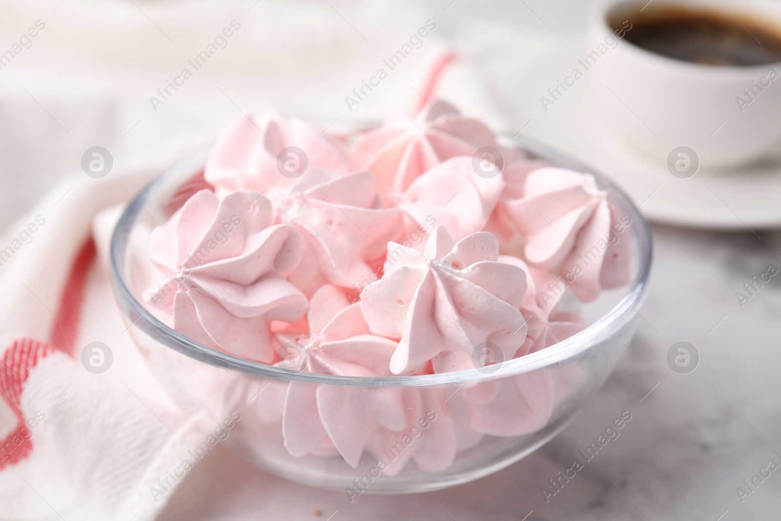 Photo of Tasty meringue cookies in bowl on white marble table