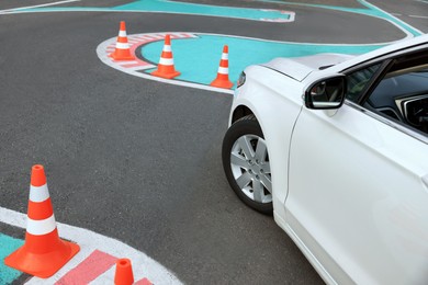 Photo of Modern car on test track with traffic cones, above view. Driving school
