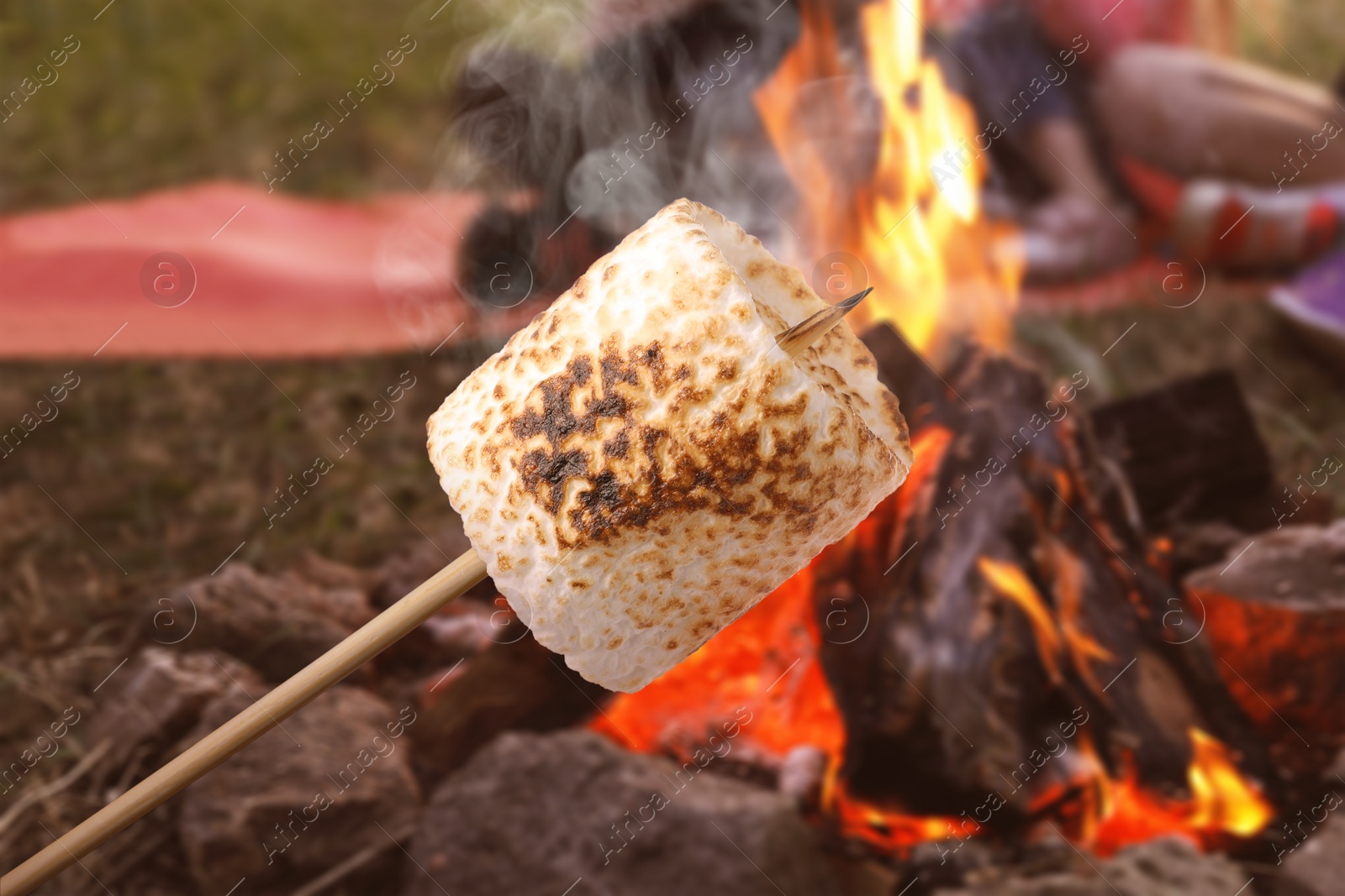 Image of Delicious puffy marshmallow roasting over bonfire outdoors