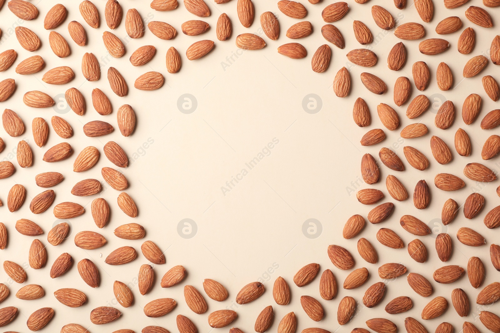 Photo of Frame made of organic almond nuts on color background, top view. Space for text