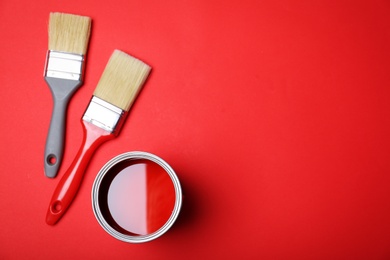 Flat lay composition with paint can and brushes on red background. Space for text