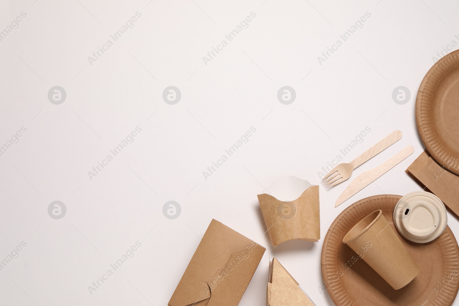 Photo of Eco friendly food packaging. Paper containers and tableware on white background, flat lay. Space for text