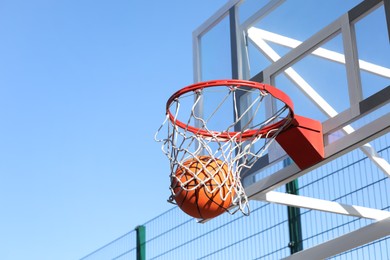 Basketball ball and hoop with net outdoors on sunny day