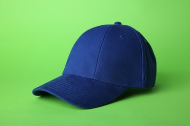 Photo of Stylish blue baseball cap on light green background