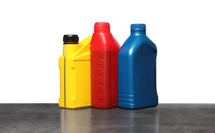 Photo of Motor oil in different containers on grey table against white background