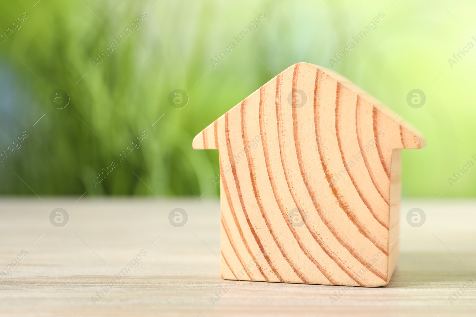 Photo of Mortgage concept. House model on white wooden table against blurred green background, space for text