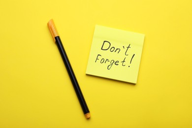 Photo of Paper note with phrase Don' t Forget and pen on yellow background, flat lay