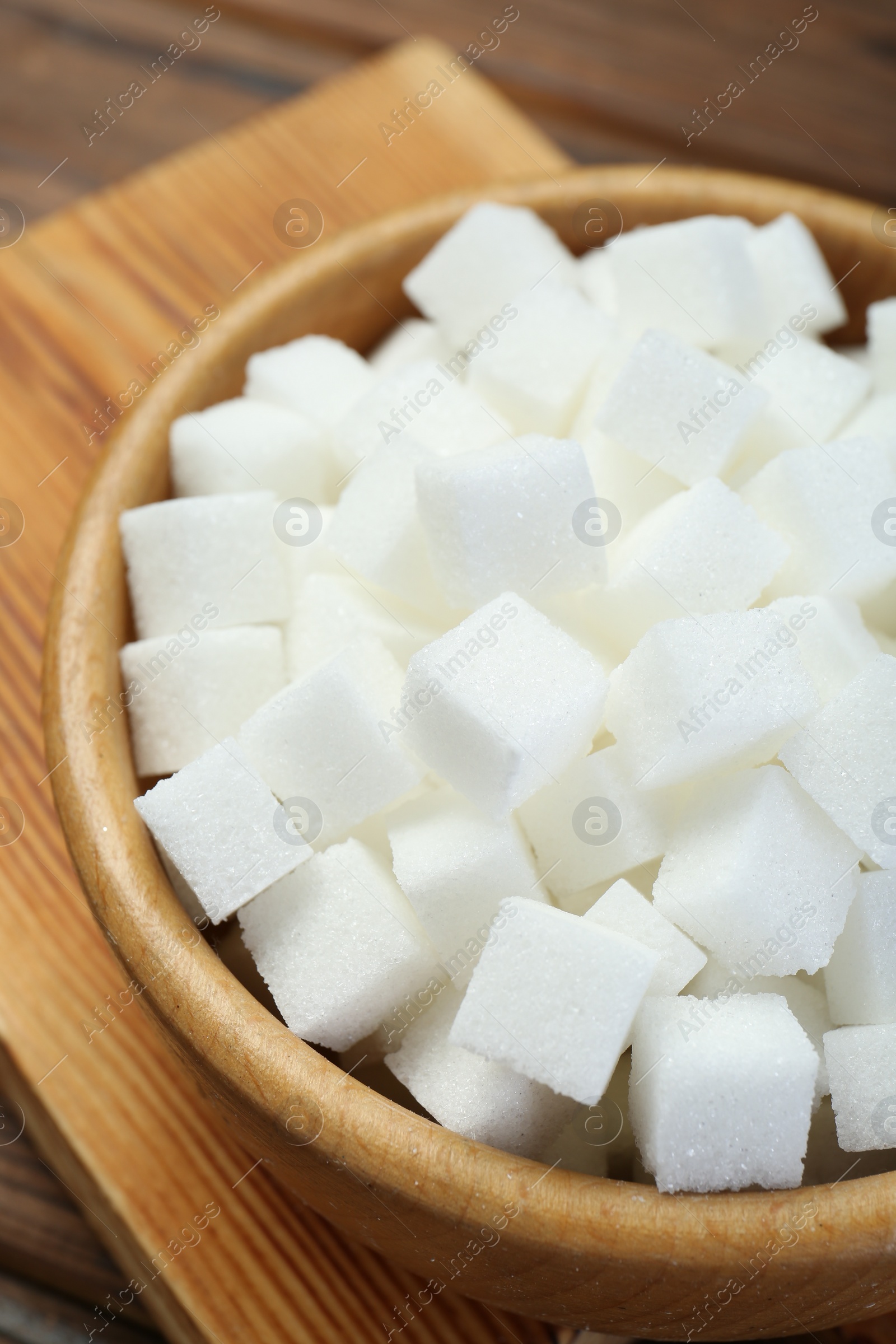 Photo of White sugar cubes in wooden bowl, closeup