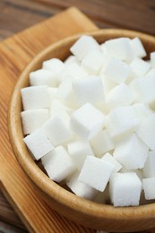 Photo of White sugar cubes in wooden bowl, closeup